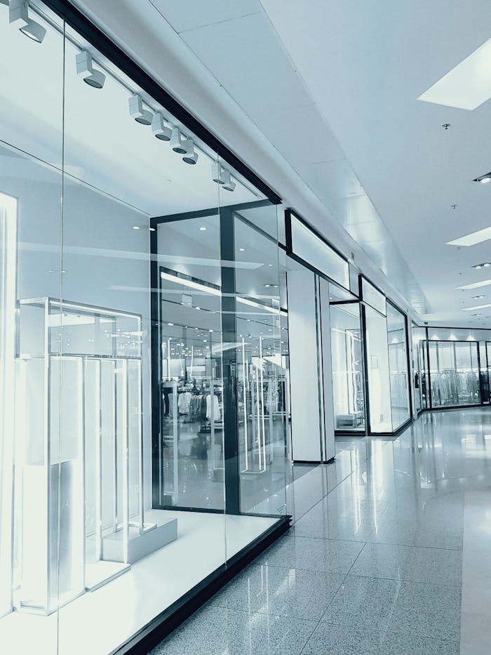 Services-03 Bright and empty shopping mall corridor with glass display walls and reflections.